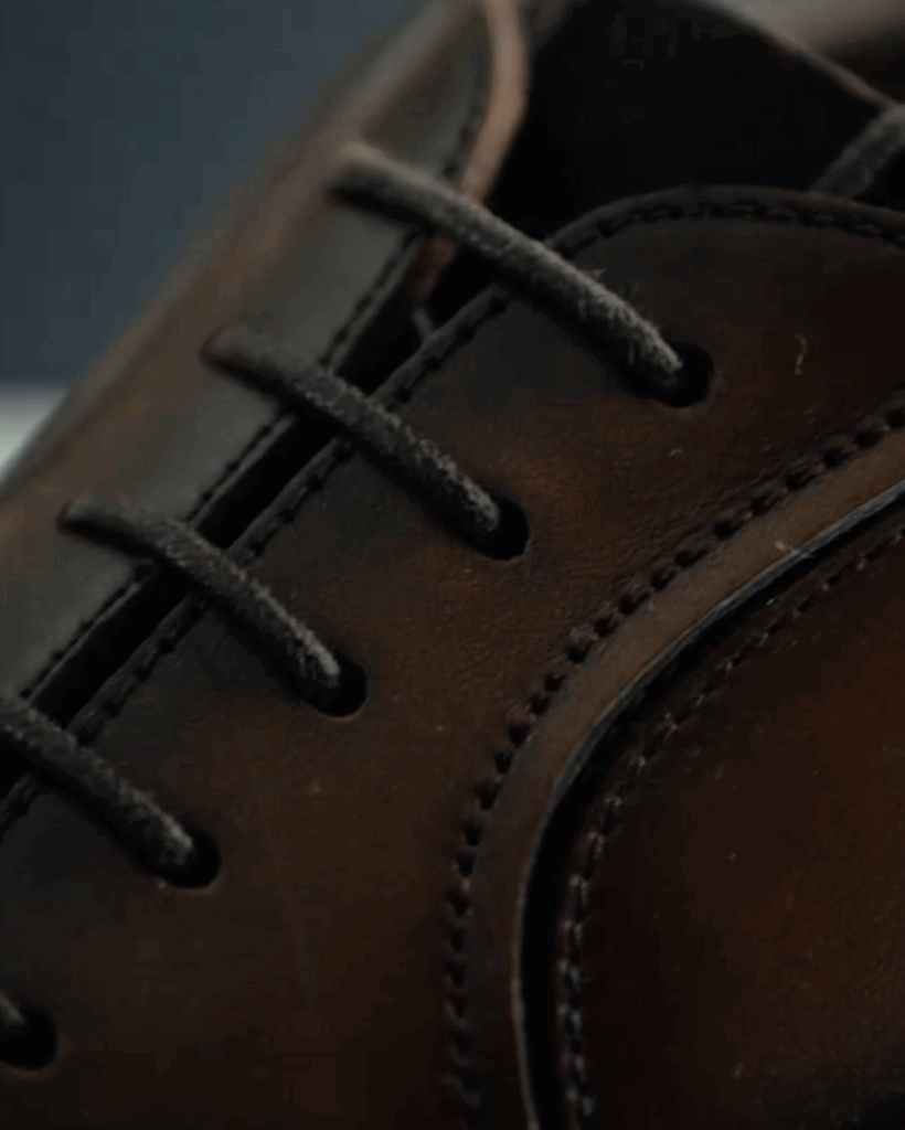 dettaglio ravvicinato di una lussuosa scarpa di pelle maschile dalla linea elegante e ricercata spiccano lacci e cuciture raffinate