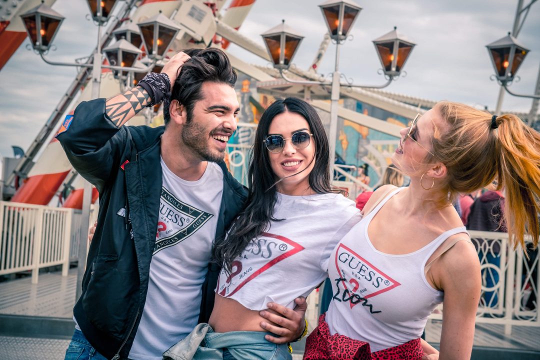 un aragazzo e due ragazze camminano abbracciati e sorridenti dopo aver fatto un giro su una ruota panoramica