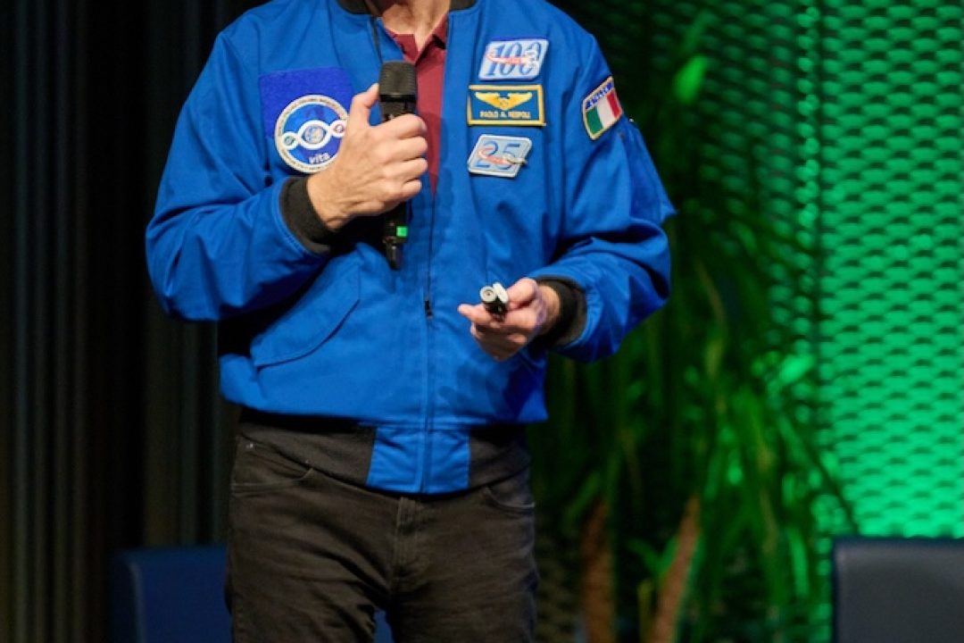 paolo nespoli parla sul palco di un evento aziendale con sfondo verde