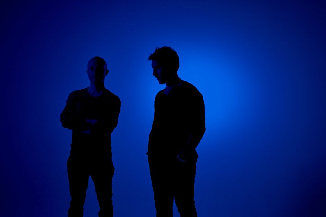 2 ragazzi in attesa posa introspettiva visti in silhouette di una luce blu
